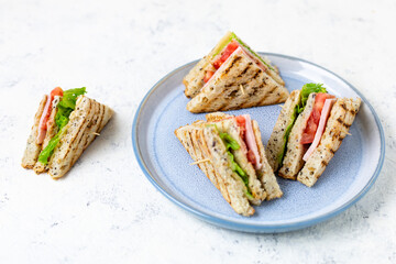 sandwich with ham cheese tomatoes lettuce onions on plate. Classic club sandwich with whole grain...