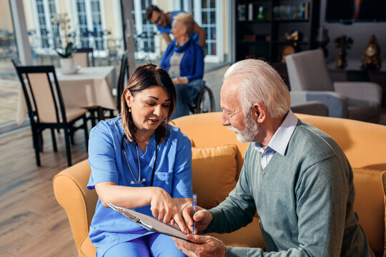 Female nurse talking to senior man at nursing home.