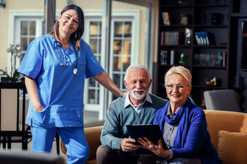 Fototapeta premium Portrait of senior couple with female nurse at nursing home.