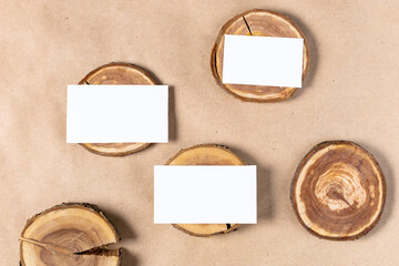 empty white business card mock up on wooden cut tree section on beige background.