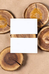 empty white business card mock up on wooden cut tree section on beige background.