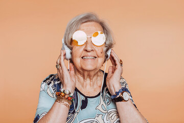 Funny happy smiling elderly grandmother portrait listening music with headphones at studio. Senior...