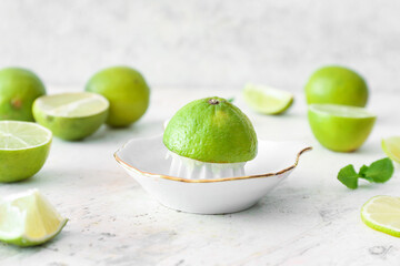 Ceramic juicer and limes on light background