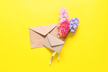 Envelopes and beautiful hyacinth flowers on yellow background