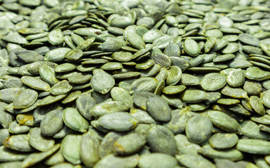 Background texture of green pumpkin seeds. Organic food, selective focus.