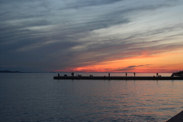 Fototapeta na wymiar Sunset time in beach , people are fishing watching sunset , Colorful Sun Croatia Zadar