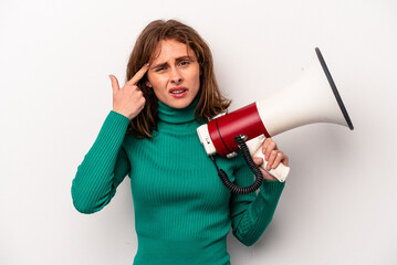 Young caucasian woman holding a megaphone isolated on white background showing a disappointment gesture with forefinger.