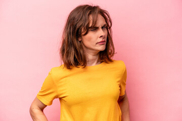 Young caucasian woman isolated on pink background frowning face in displeasure, keeps arms folded.