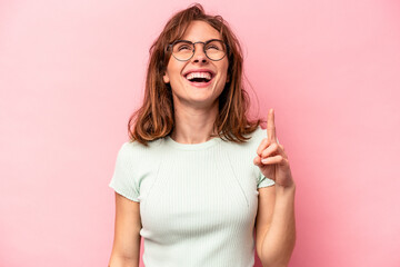 Young caucasian woman isolated on pink background indicates with both fore fingers up showing a...