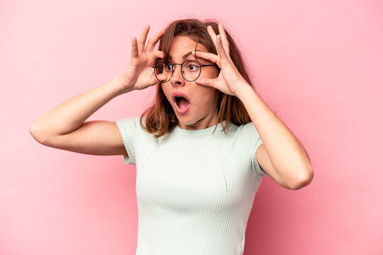 Young caucasian woman isolated on pink background keeping eyes opened to find a success opportunity.