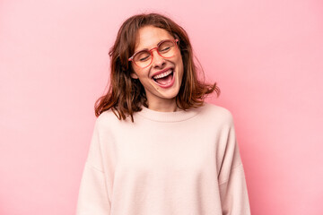 Young caucasian woman isolated on pink background laughs and closes eyes, feels relaxed and happy.