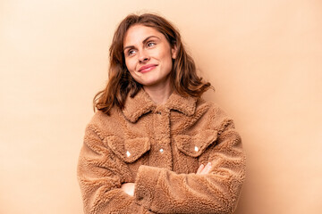 Young caucasian woman isolated on beige background dreaming of achieving goals and purposes