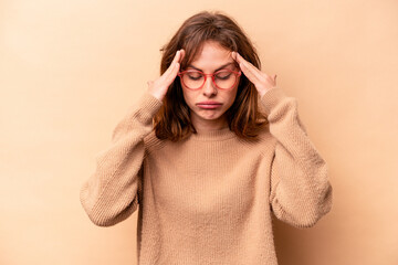Young caucasian woman isolated on beige background touching temples and having headache.
