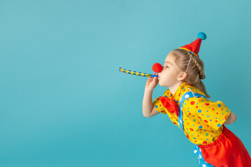 Funny kid clown against blue background. Happy child playing with festive decor. Birthday and 1 April Fool's day concept - obrazy, fototapety, plakaty