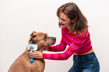 Young caucasian woman combing her dog isolated on white background