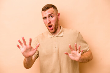 Young caucasian man isolated on beige background rejecting someone showing a gesture of disgust.