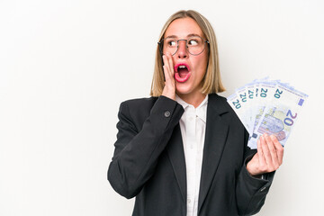 Young business caucasian woman holding banknotes isolated on white background is saying a secret...