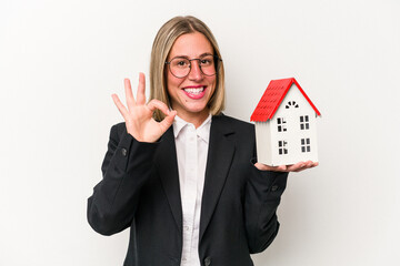 Young business caucasian woman holding a toy house isolated on white background cheerful and...