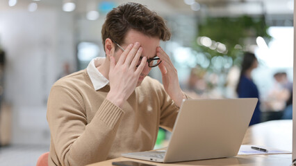 Young Man having Headache while Working on Laptop 