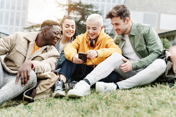 Group of happy college student friends sharing moments on cell phone app in the University campus grass