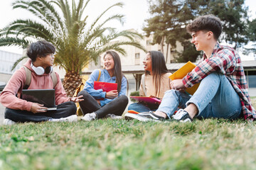 Group of multiracial international exchange university student friends sitting on the grass in the colege campus