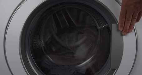 Person closing washing machine door, ready to wash clothes, close up