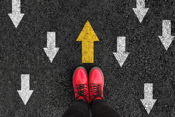woman boots on asphalt and opposing direction arrows on asphalt ground, personal perspective...
