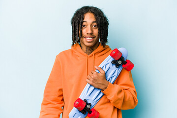 Young African American skater man isolated on blue background happy, smiling and cheerful. © Asier