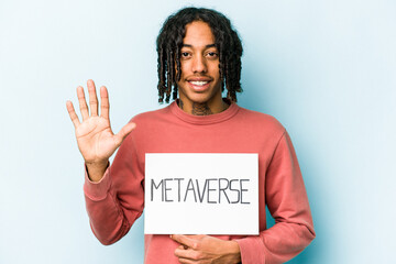 Young African American man holding metaverse placard isolated on blue background smiling cheerful showing number five with fingers.