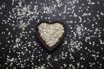 Oatmeal heart isolated on a dark background, with place for an inscription. Bunting heart symbol. Heart of cereals. Healthy eating. heap of oat flakes in a shape of heart shot from above