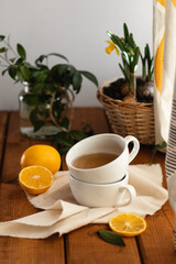 Tea with lemon  in white cup at old wooden board in rustic style. On a light background with spring greens.
