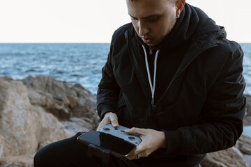 Young man operating a drone over the sea