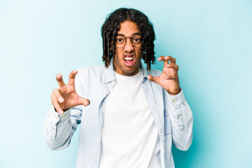 Young African American man isolated on blue background upset screaming with tense hands.