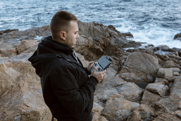 Young man operating a drone over the sea