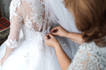 Obraz na płótnie Canvas The bride's wedding fees. bridesmaids help to put on a dress