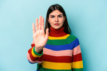 Young caucasian woman isolated on blue background standing with outstretched hand showing stop...
