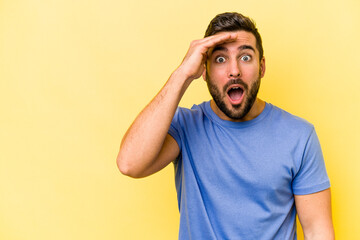 Young caucasian man isolated on yellow background shouts loud, keeps eyes opened and hands tense.