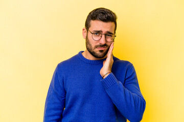 Young caucasian man isolated on yellow background having a strong teeth pain, molar ache.