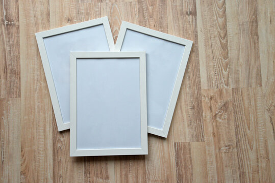 Top view of three photo frames on the wooden floor. Blank frame mockups.