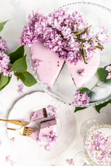 a piece of mousse cake, Delicious dessert blueberry tart with fresh berries with a bouquet of purple blooming lilacs, vertical image place for text