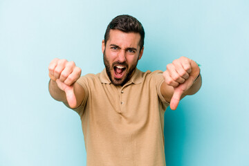 Young caucasian man isolated on blue background showing thumb down and expressing dislike.