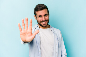 Young caucasian man isolated on blue background smiling cheerful showing number five with fingers.
