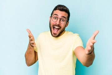 Fototapeta premium Young caucasian man isolated on blue background feels confident giving a hug to the camera.