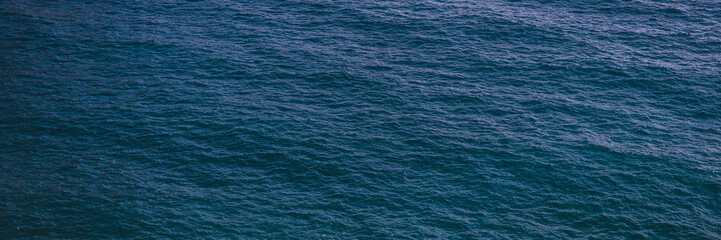 ocean or sea water textured dark blue background. surface and texture of calm shallow waves and depth. summer nature landscape. banner