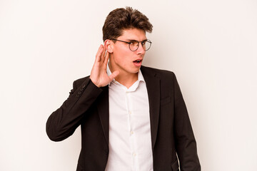 Young caucasian business man isolated on white background trying to listening a gossip.