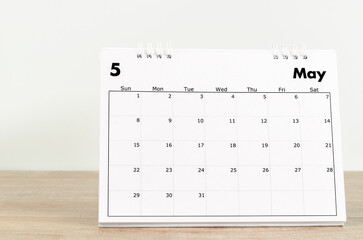 May 2022 desk calendar on wooden background.