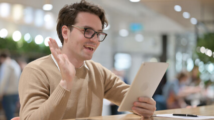 Video Call on Tablet by Handsome Young Man, in Office 