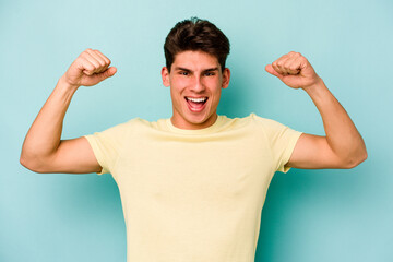 Young caucasian man isolated on blue background showing strength gesture with arms, symbol of feminine power