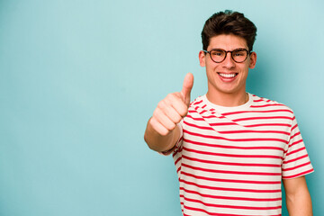 Young caucasian man isolated on blue background smiling and raising thumb up