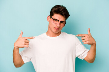 Young caucasian man isolated on blue background person pointing by hand to a shirt copy space, proud and confident
